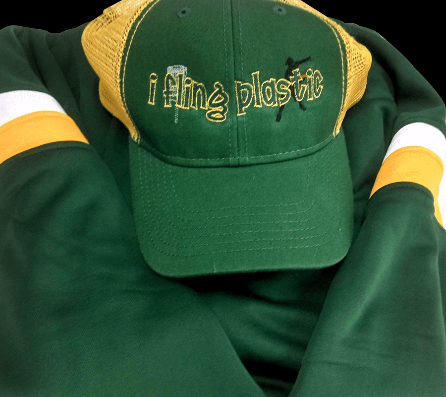 A green and yellow hat sitting on top of a jacket.